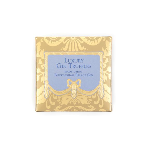 A golden chocolate box with blue writing and centre, stating "Luxury Gin Truffles, made using Buckingham Palace Gin." A golden chocolate box with blue writing and centre, stating "Luxury Gin Truffles, made using Buckingham Palace Gin."