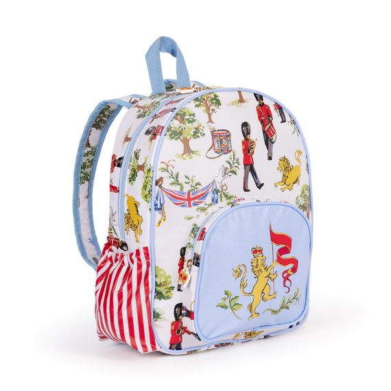 The Children's Royal Guard Backpack, featuring the new designs with Royal Guards marching through the woods trumpeting and drumming, as well lions with the floral symbols of the four British nations and trees. The front pocket is blue and features a lio The Children's Royal Guard Backpack, featuring the new designs with Royal Guards marching through the woods trumpeting and drumming, as well lions with the floral symbols of the four British nations and trees. The front pocket is blue and features a lio