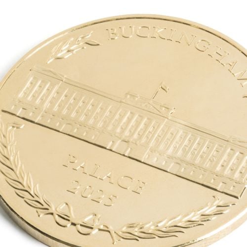 Buckingha Palace 2025 Coin featuring facade of Buckingham Palace with laurels bordering. 